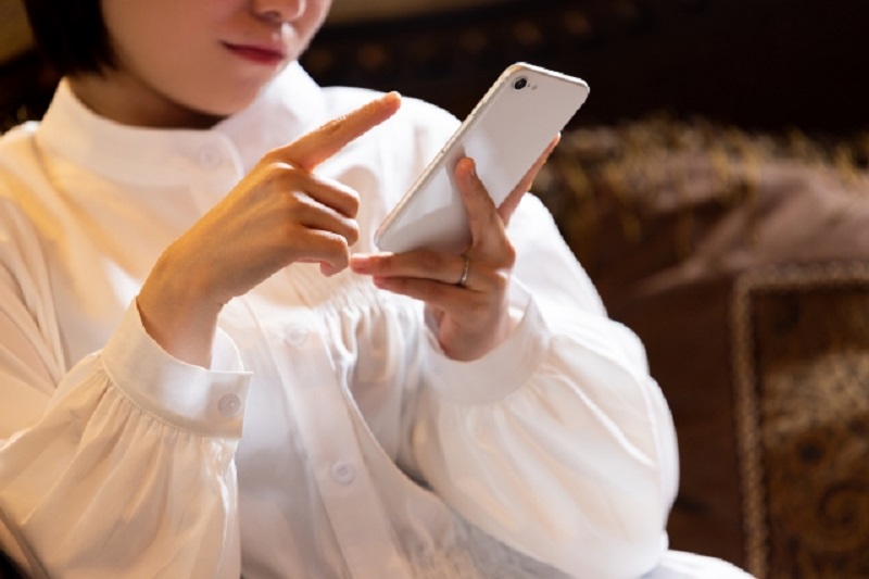 ソファに座りスマホを操作する女性